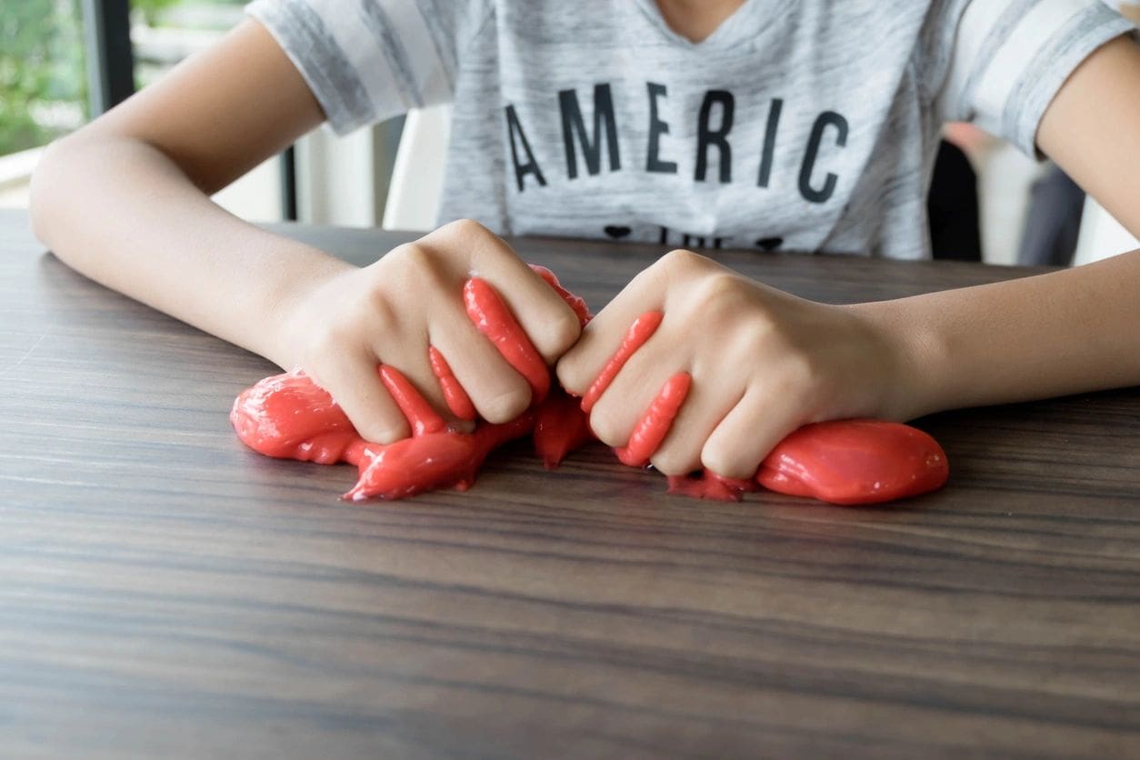 A person with red nails and shirt on playing with clay