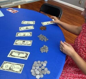 A woman sitting at a table with coins and money.