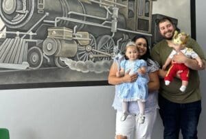 A family posing in front of a train mural.