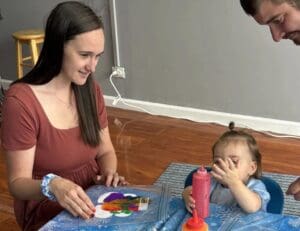 A woman and child sitting at a table with a painting.