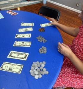 A woman sitting at a table with coins and paper money.