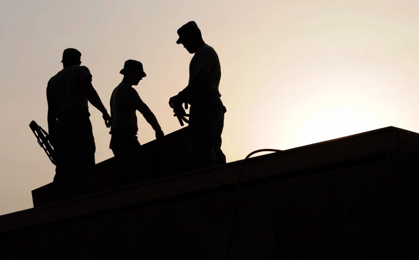 Three men are working on a roof.