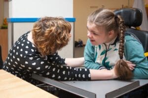 Two girls are playing arm wrestling in a classroom.